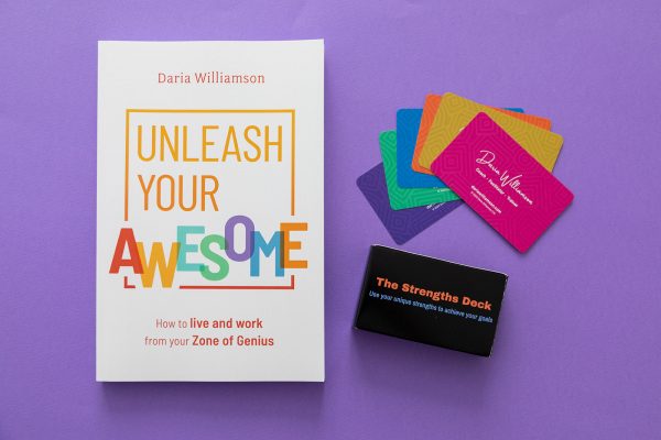 A photo of 'Unleash Your Awesome' book, with The Strengths Deck cards and box, on a purple background
