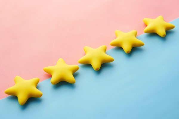 Five yellow 3D stars lying on a pink and blue background. They follow the diagonal line between the two background colours.