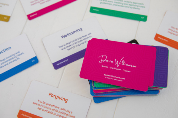 Close up of The Strengths Deck cards, showing the colourful backs, and the fronts which have the name of the strength and the definition, along with the strengths group colour and name